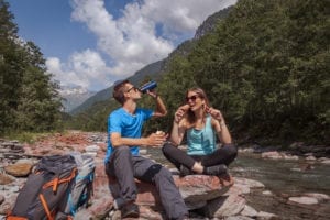 A couple enjoying a snack near a river on a day hike in Yosemite.