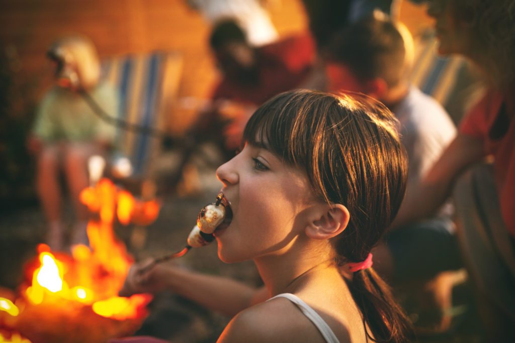 A girl eating a roasted marshmallow.
